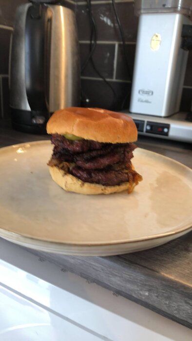 Hemlagad hamburgare på tallrik i kök.