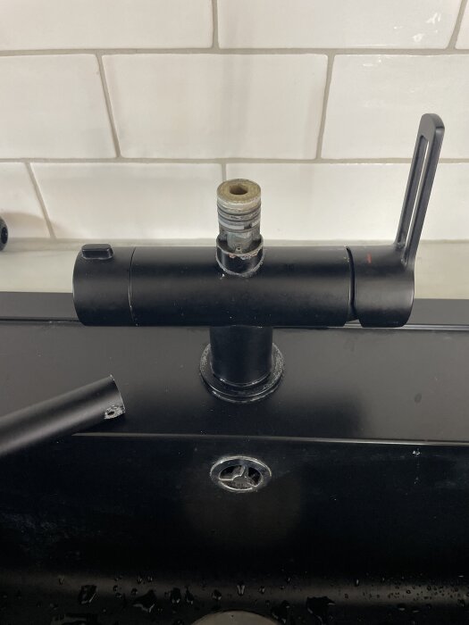 Svart köksblandare med borttagen pipnippel, stående framför vitt kakel. En fråga om demontering har ställts i inlägget.