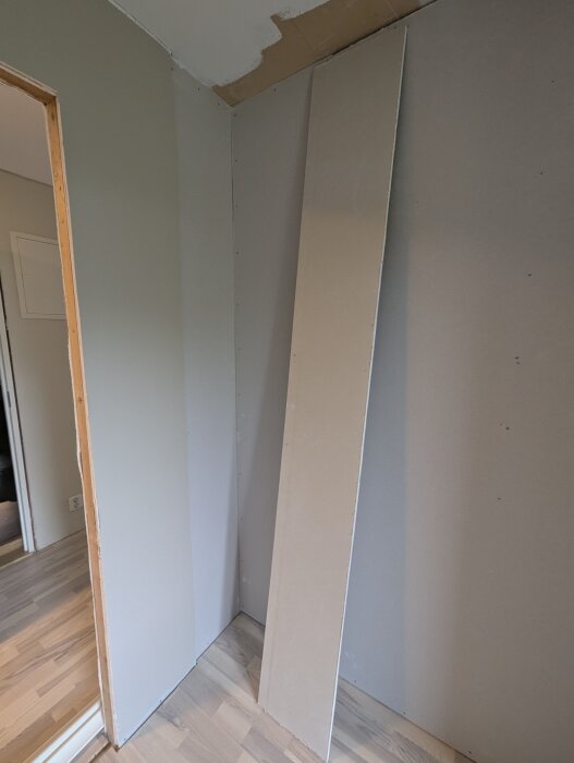 En gipsskiva lutar mot en vägg i ett rum under renovering, dels oskyddad vägg synlig.