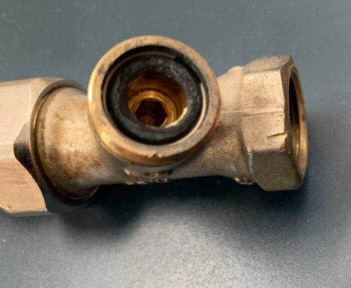 En närbild på en metallisk returventil placerad på en mörk yta.