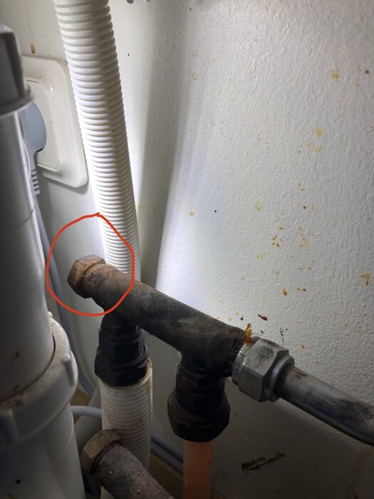 Rostig ventil under diskbänk, eventuellt för att stänga av inkommande vatten till köksblandare, markerad med röd cirkel.