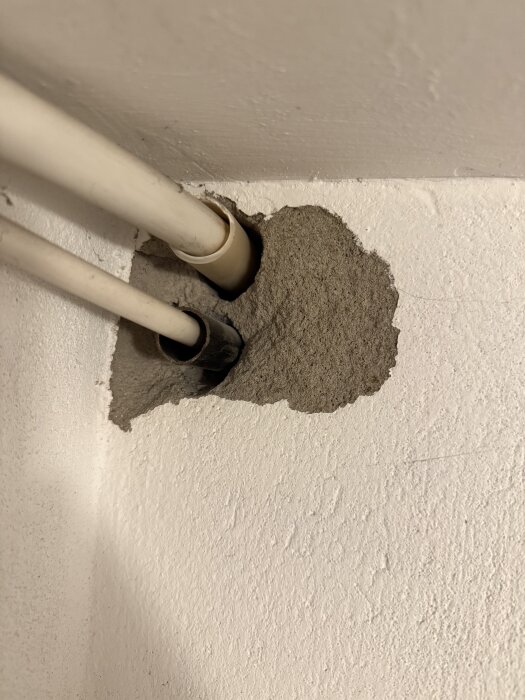 Hål i innervägg av lättbetong, två rör går genom väggen. Ingen blå nyans synlig, bild av oro för möjlig radonrisk i hus från 1965.