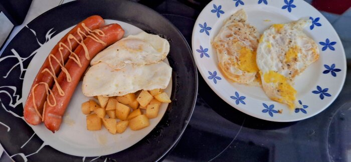 Tallrik med korv toppad med dressing, stekta ägg och stekt potatis, samt en separat tallrik med två stekta ägg.