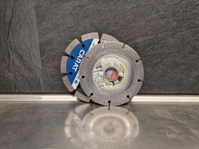 Två diamantklingor, en uttöjd och en ny, på en metallisk yta mot en mörk bakgrund.