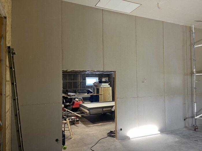 Väggar med OSB och gipsskivor, klar installation i byggnadens höga del, synlig öppning med insikt i arbetsområde.