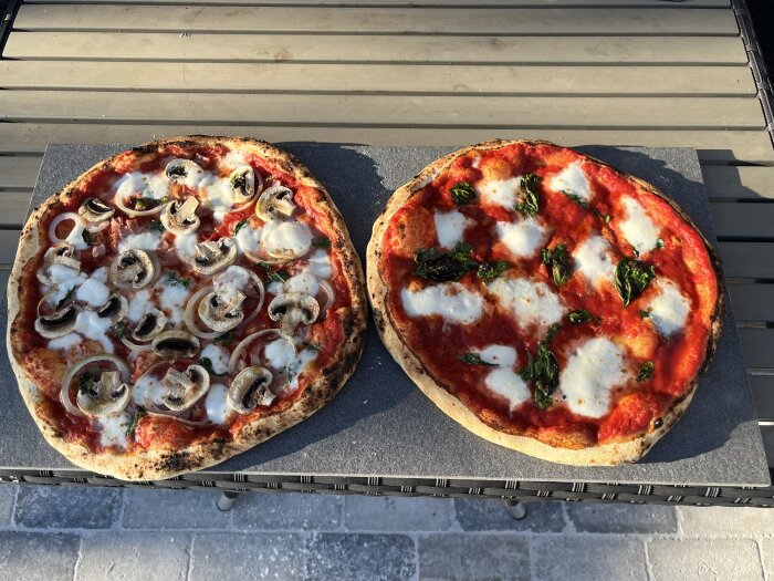 Två hemmagjorda pizzor på ett bord, en med svamp och lök, och en med mozzarella och basilika.