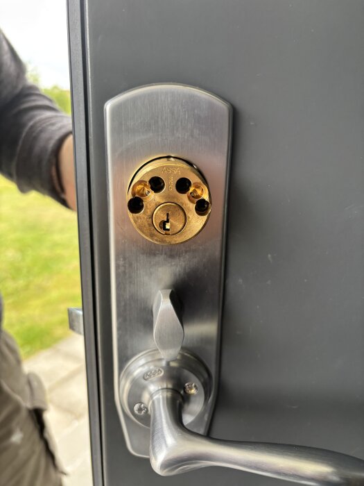 Närbild på en dörr med ett Assa-lås där pilarna pekar i olika riktningar och några spärrar saknas.