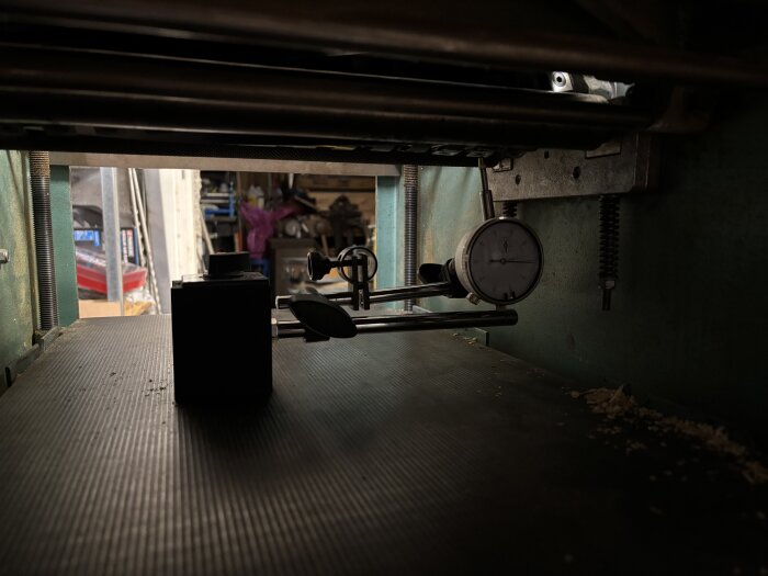 Mätinstrument och verktyg under en träbearbetningsmaskin, med fokus på en mätklocka använd vid inställning av kutter.