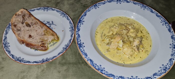 Fisksoppa med curry, fänkål, purjolök och bitar av fisk i en blåvit skål, serverad med råglevainbröd med valnötter och olivolja.