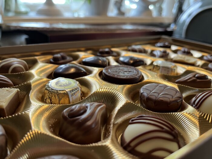 En närbild av en chokladask fylld med olika praliner, perfekt för en mysig ESC-kväll framför tv:n.