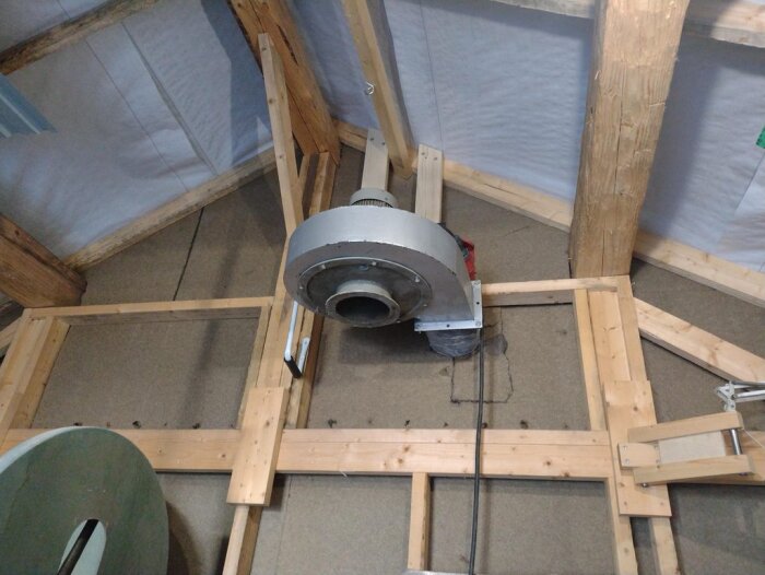 Spånsug monterad på väggen i en verkstad, med träram och isolering, utan cyklon, för att blåsa ut damm.