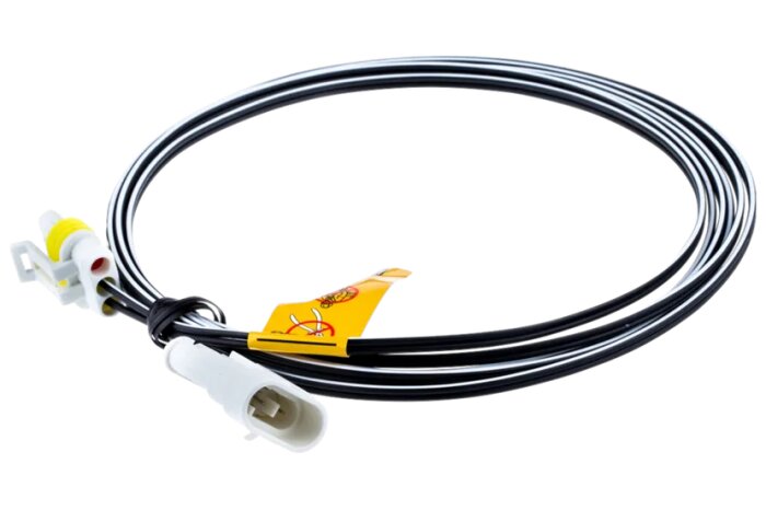 Svart och vit lågspänningskabel med vita kontakter och gul märkning ligger i en spiral.