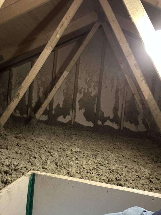 Vind med isolering och takkonstruktion där takstolar är exponerade.