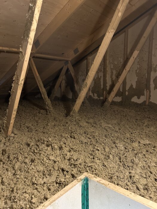 Vindsutrymme med synliga takstolar och isolering i golvet, tänkt för byggprojekt av plattform för förvaring.