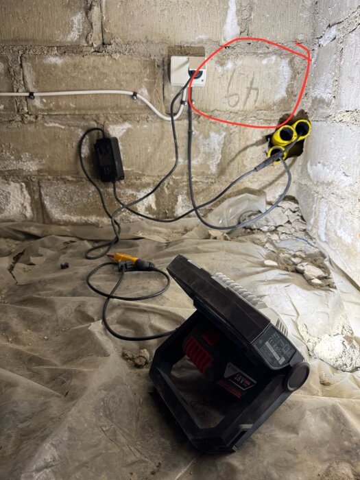 Kabeldragning och en väggkontakt mot en betongvägg med "6h" skrivet, markerat i rött. Verktyg ligger på plastskyddad golvyta.