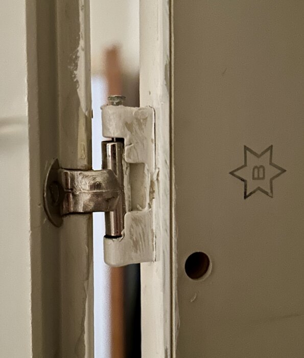 Gammalt gångjärn på en platsbyggd garderob från 60-talet, visar slitage och slitna ytor, sätts i fråga om ersättningsalternativ.