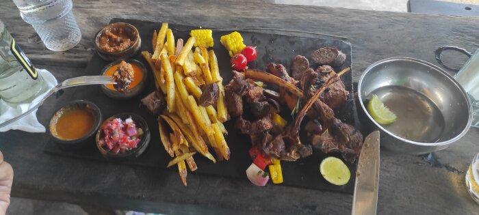 Serverad planka med biff, pommes frites, majs, limeskiva, såser och grönsakstillbehör på Coco Beach, Dar es Salaam.