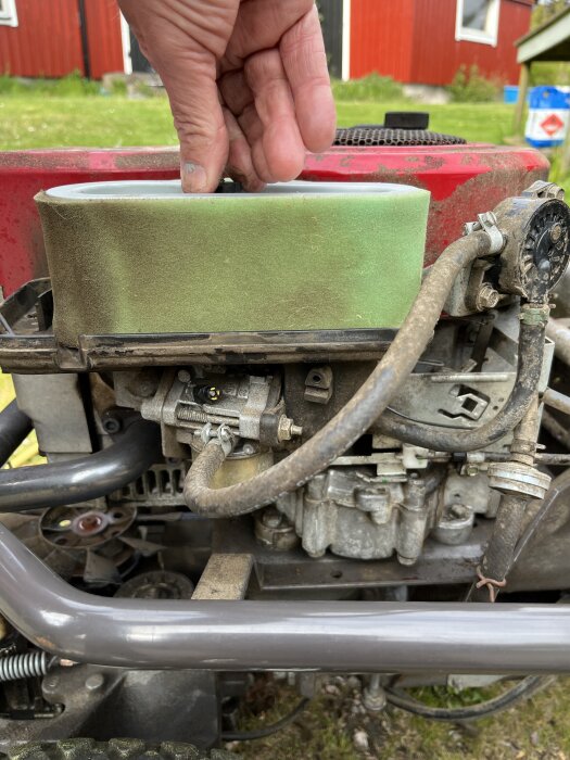 Hand justerar gasreglage på Husqvarna Rider 13 Bioclip motor, fokus på grön komponent och bränsleslangar.