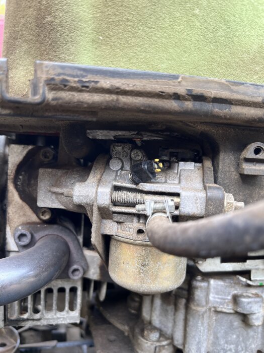 Motor på Husqvarna Rider med förgasare och armar markerade i gul och röd cirkel för att lösa gasreglageproblem.