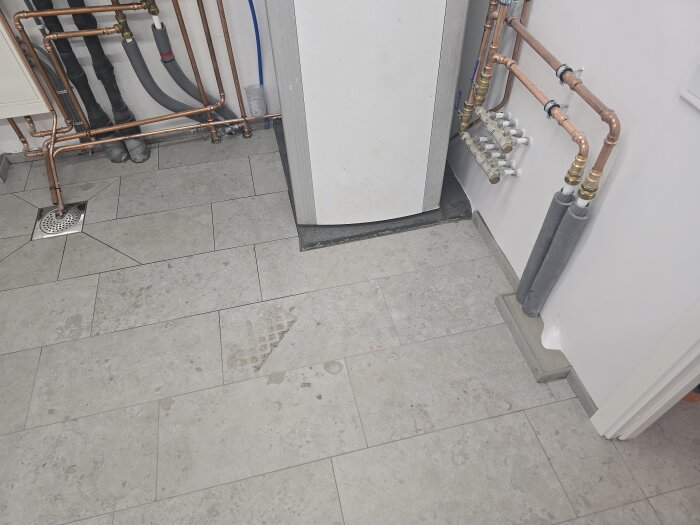 Kaklat golv i maskinrum med synliga kopparrör och olika installationer längs väggarna, redo för att ansluta till maskineriet.