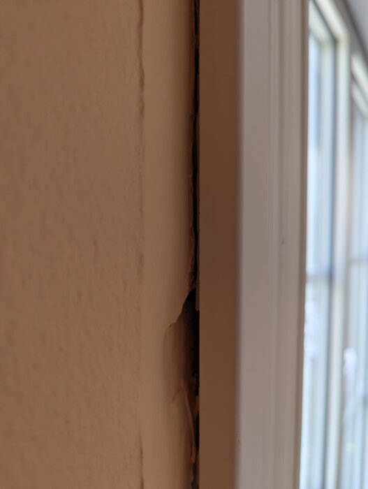 Glipa mellan fönsterfodret och väggen med synlig spricka, vilket orsakar drag i hemmet.