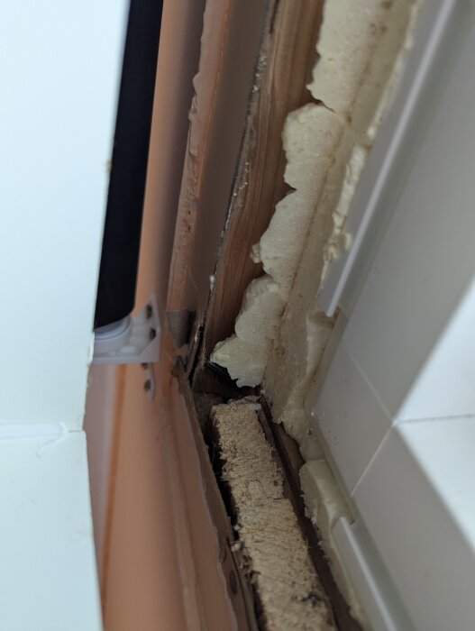 Fönster med ett löst fönsterfoder och synlig glipa, samt isolering som sticker ut.