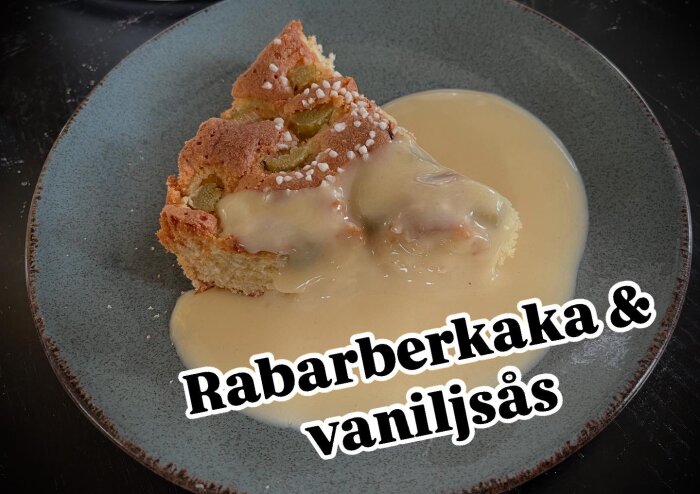 En bit rabarberkaka täckt med vaniljsås på en grå tallrik.