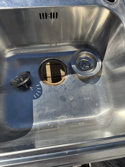 Diskbänk för utekök med hål för avlopp och två avloppssilar.