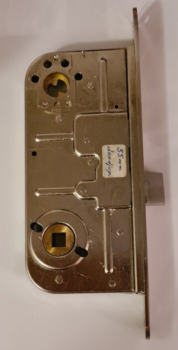 ASSA ruko låskista i metall med etikett "55 mm döndjup", visas från sidan med mekanismens detaljer synliga.
