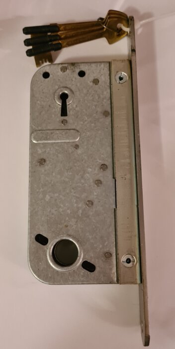 ASSA säkerhetslås 9001 med tillhörande tre nycklar på en ring, låskista i metall.