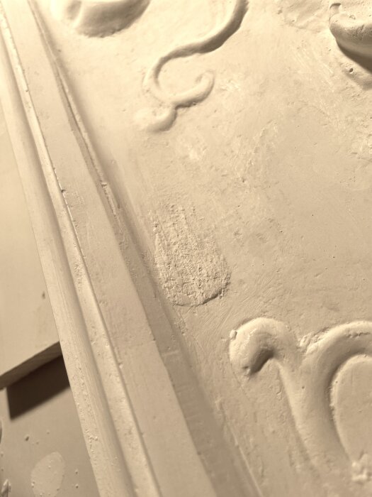 Provgjutning med synliga glasfibernät och tydliga detaljer, inklusive ojämn spackling, på en yta med dekorativa mönster.