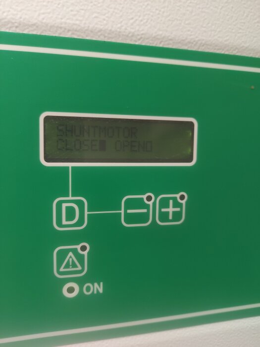 Display på värmepump med texten "SHUNTMOTOR" och indikation för "CLOSE" och "OPEN", samt symboler för justering.