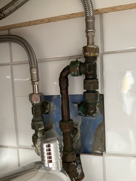 Gammaldags rör och kopplingar med flexibla metallslangar under ett tvättställ, saknar kulventil.