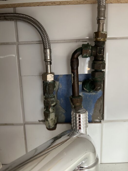 Rörkopplingar under handfat med metallslangar och gamla anslutningar, ingen kulventil synlig.
