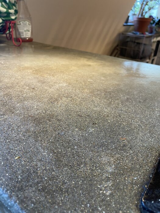 Grov yta på en sliten betongbänkskiva i köket, med ojämnheter och behov av renovering.