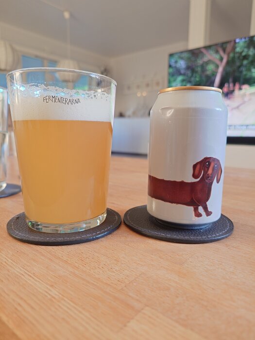 Glas med öl från Fermenterarna och en ölburk med taxmotiv på ett bord, inomhus.