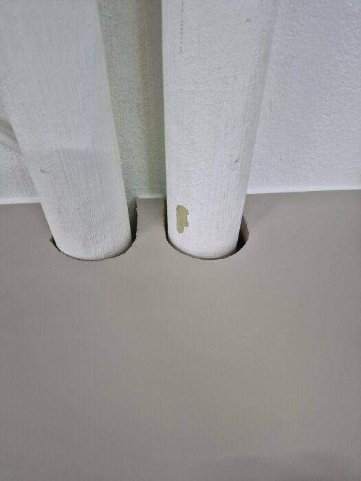 Två vita vattenrör som går genom hål i en bänkskiva, avsedda för anslutning till tvättmaskin eller diskställ.