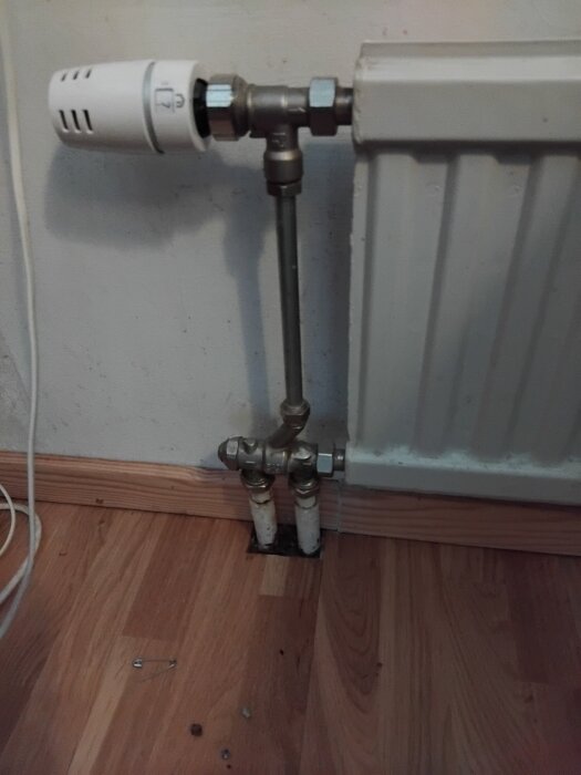 Radiator med ett-rörssystem och termostat, rör mot golv utan bypass.