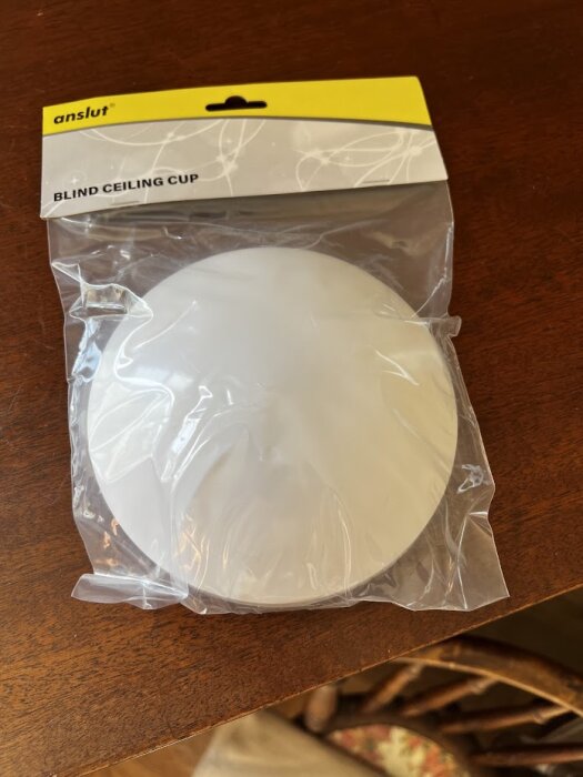 Förpackning med en "Blind Ceiling Cup" från märket Anslut, synlig genom plasten, liggande på ett bord.