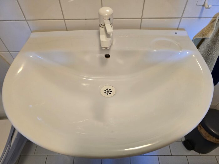 Vit Ifö-handfat i badrum med kran och avloppshål.