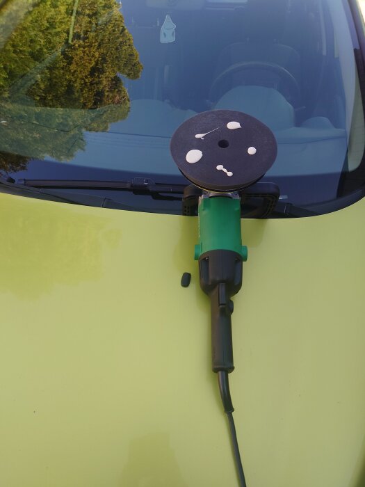 Bilpolering med polermaskin på motorhuv.