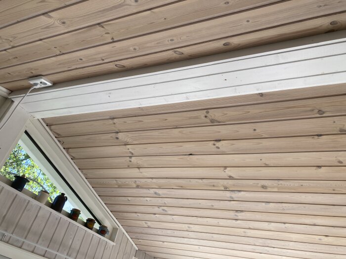 Träpanelerat innertak i vinterbonat uterum, notera ventilationsöppning med små krukor i fönstret.