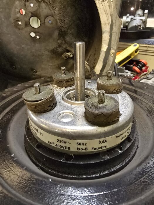 Motor med fyra slitna vibrationsdämpare omgivna av en metallhölje där etiketten anger 220V, 50Hz, 0,8A; del av ett ftx-system.