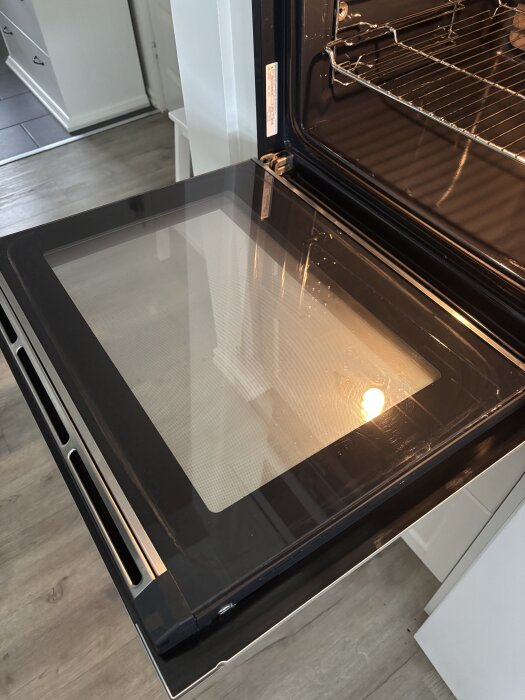 Öppen ugn med glaslucka, svår att ta loss för rengöring.