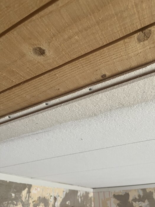 Träbrädor i taket ovanför en gipsskiva i rum under renovering.