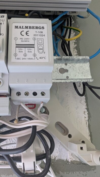 Transformator Malmbergs T-108 med anslutna kablar, monterad på vägg. Visa primär och sekundär anslutning. Bakgrunden visar elektriska ledningar.