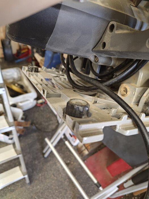 Bilden visar en närbild av en sågmaskin med skena där en kabel och en justering skruv syns i förgrunden.