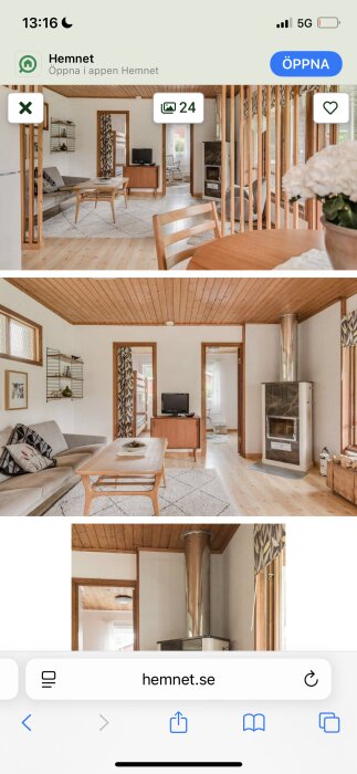 Vardagsrum i en stuga med trägolv, öppen spis, soffa och matbord. Trätak och panelväggar med dekorationer.