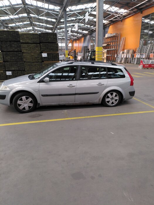 En bil parkerad inomhus på Hornbach, omgiven av byggmaterial som isolering och stegar.