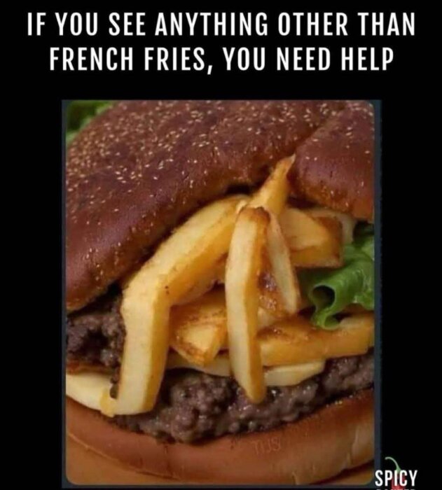 Hamburgare med pommes frites mellan bröden, salladsblad och ost synligt. Brödet är strösslat med sesamfrön.